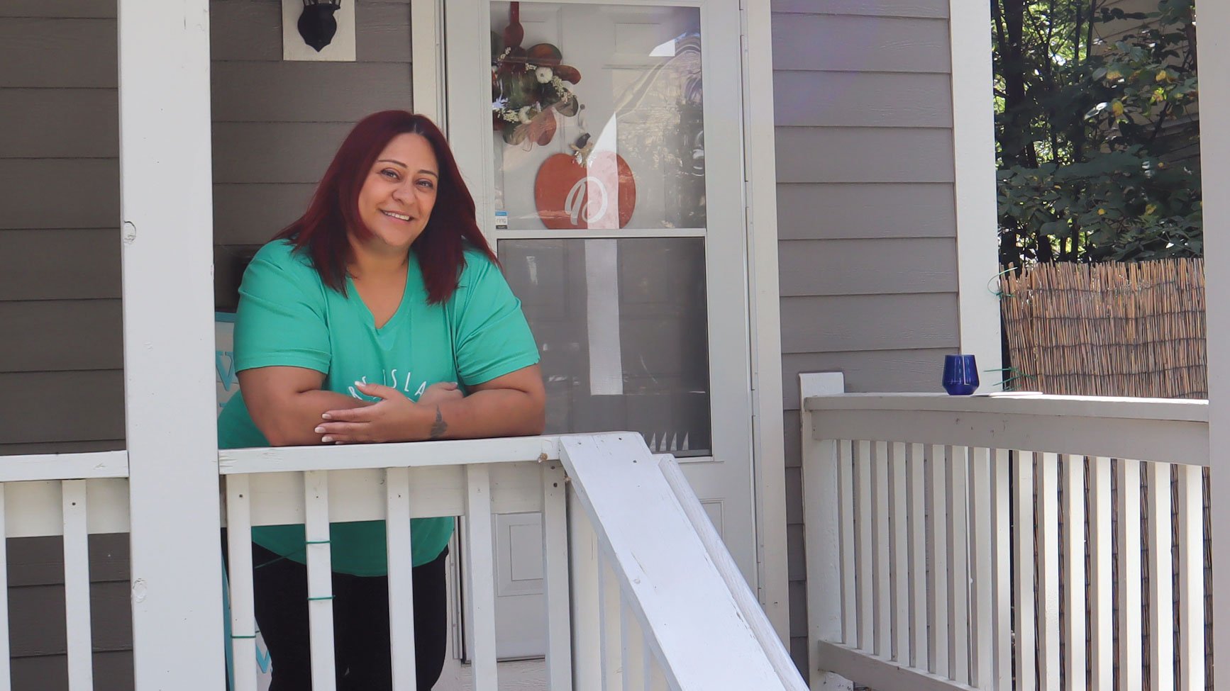 Michelle standing on her porch in front of her Habitat home.