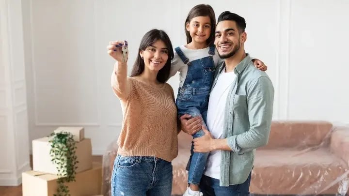 Smiling homeowner family holding up a house key.