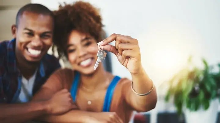 Smiling couple holding up a house key.