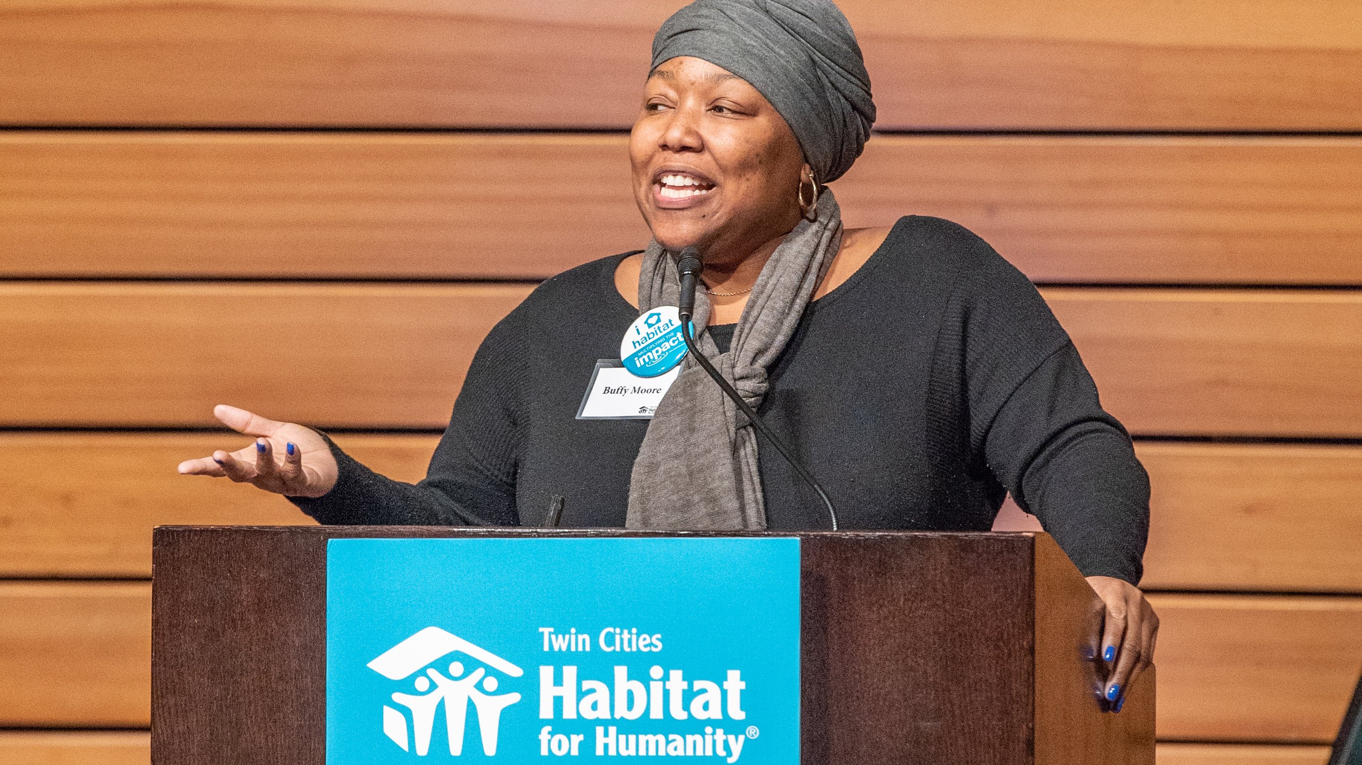 A woman speaking at a podium with a sign that says 