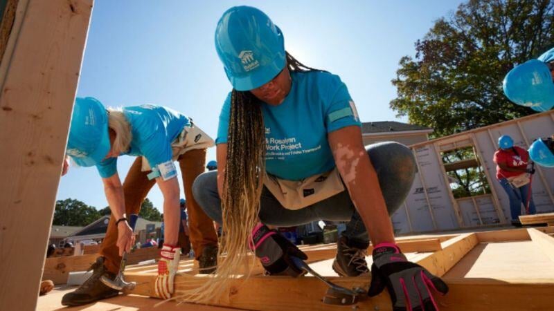 Volunteer placing a wood beam in construction.