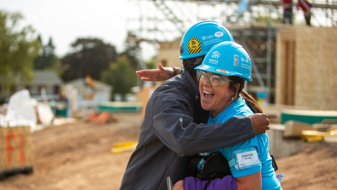 Two construction volunteers hugging.