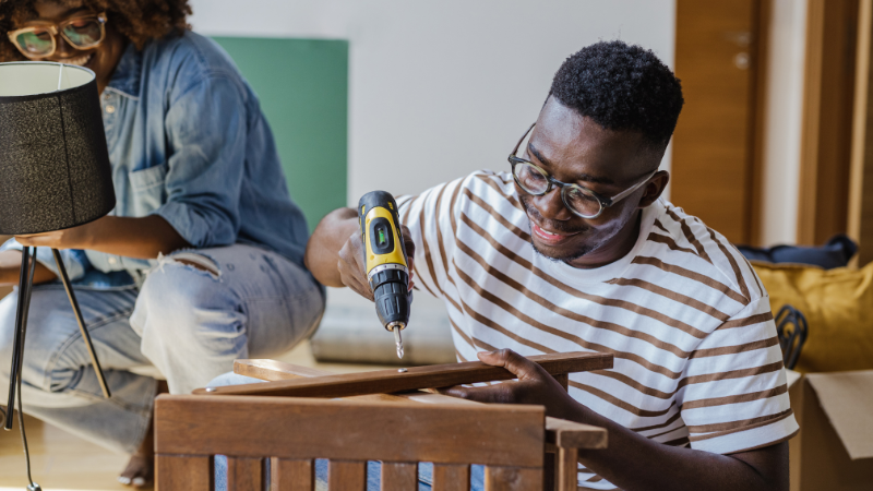 Man using a power tool to assemble furniture.