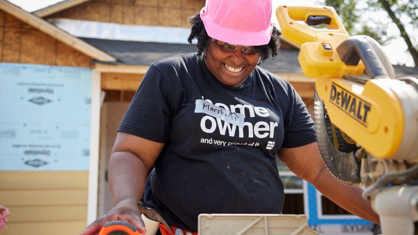 A Habitat homeowner smiles while volunteer on a site.
