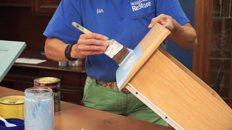 Jan Hagerman painting a wooden drawer.
